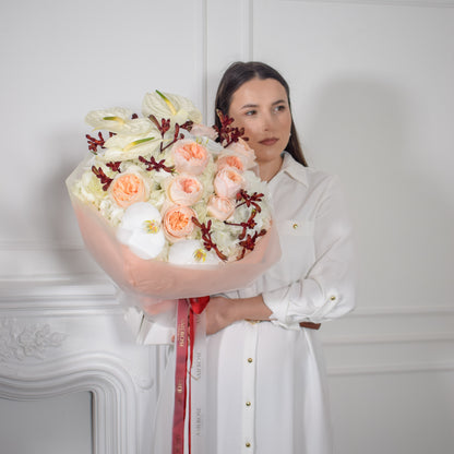 AMEROSE Bordeaux bouquet — Juliet David Austin roses, white orchids and burgundy foliage, held by model in white dress