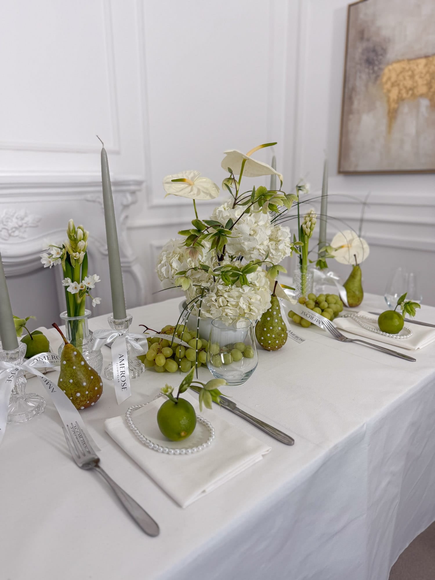 Elegant table setting with green and white decor, including pears, apples, and white and green flowers by AMEROSE.