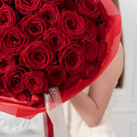 Close-up of deep red roses with signature AMEROSE ribbon in The Classic Roses luxury bouquet