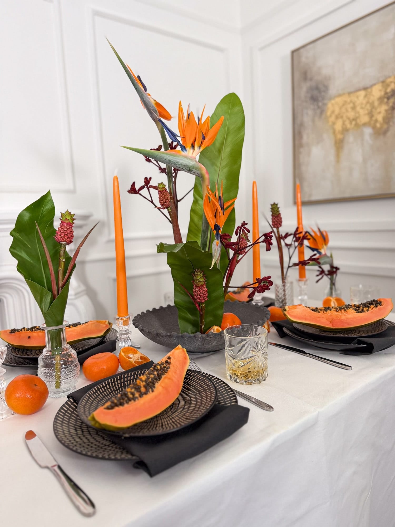 Dining table set with papaya, candles, and tropical flowers for corporate events by AMEROSE London