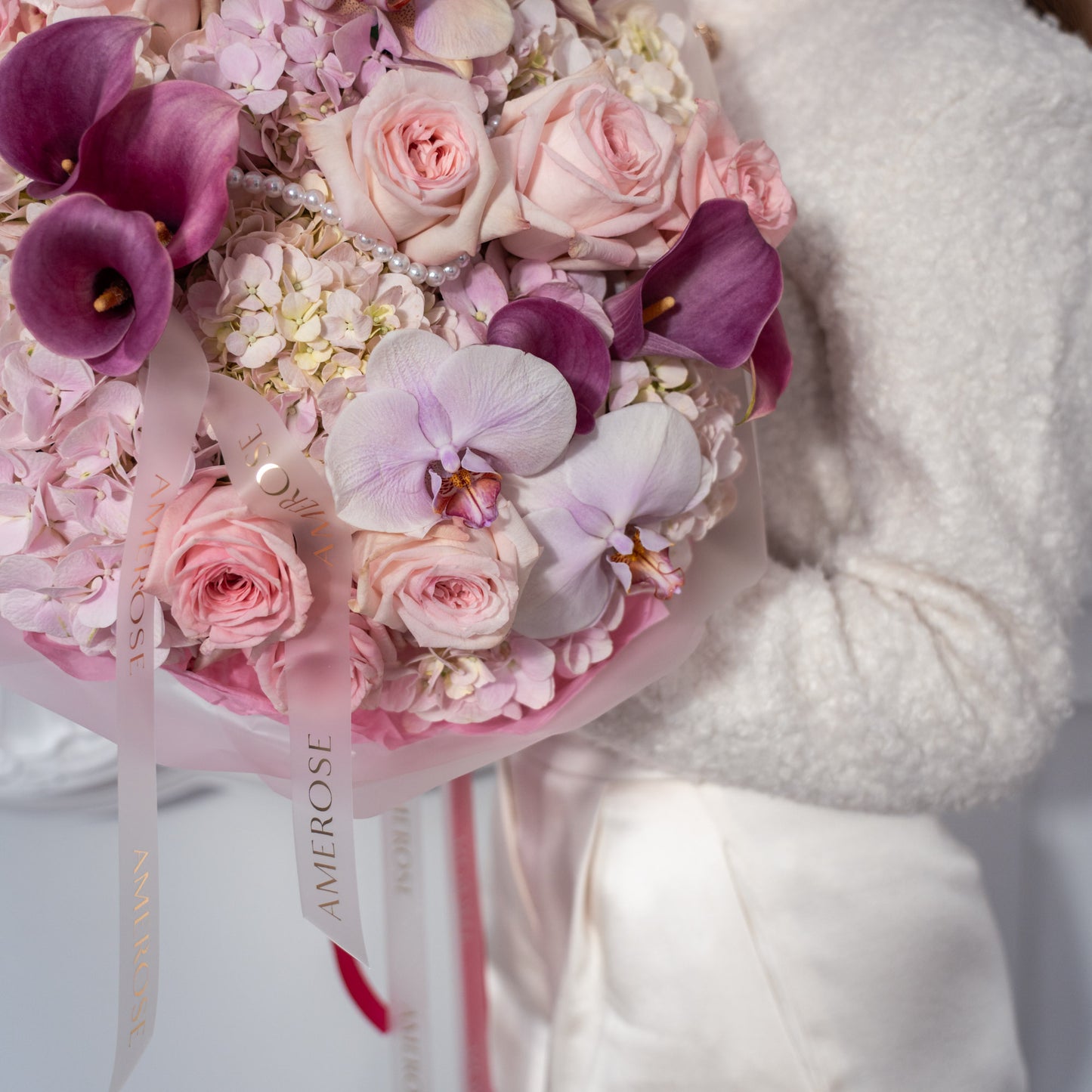 Close-up of blush garden roses, purple calla lilies, pink hydrangeas, lavender orchid and pearl strand detail with AMEROSE ribbon — luxury romantic bouquet London