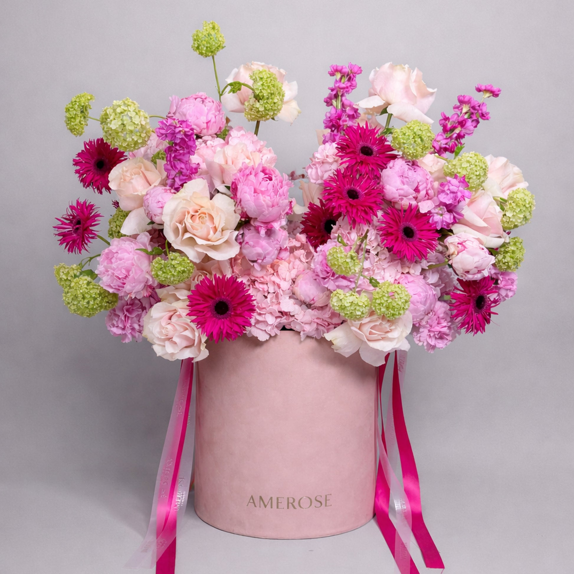 Floral arrangement in a pink box with 'AMEROSE' branding on a gray background
