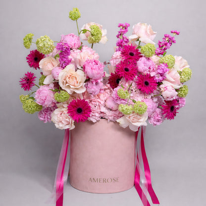 Floral arrangement in a pink box with 'AMEROSE' branding on a gray background