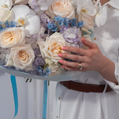 Close-up of cream garden roses, white orchids, blue forget-me-nots and lavender hydrangeas with turquoise AMEROSE ribbon — luxury blue bouquet detail London