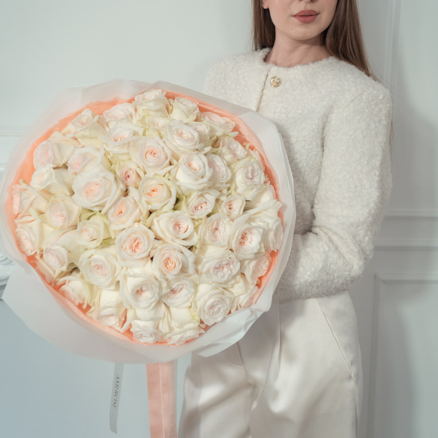 Woman holding an oversized luxury bouquet of Sweet O'Hara white garden roses elegantly wrapped, and AMEROSE ribbon — premium flower delivery London