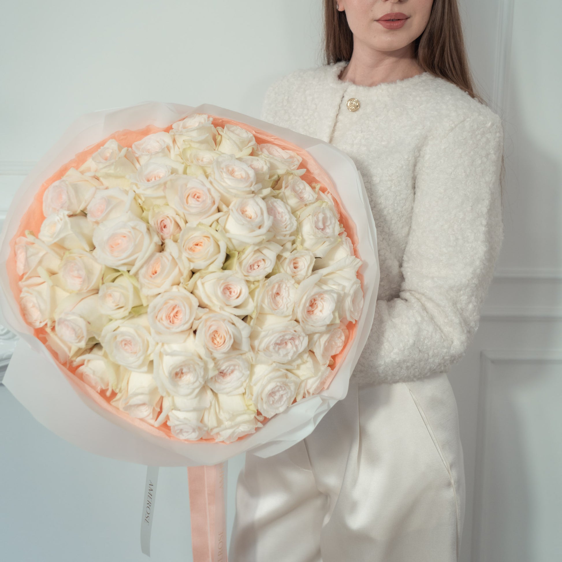 Woman holding an oversized luxury bouquet of Sweet O'Hara white garden roses elegantly wrapped, and AMEROSE ribbon — premium flower delivery London