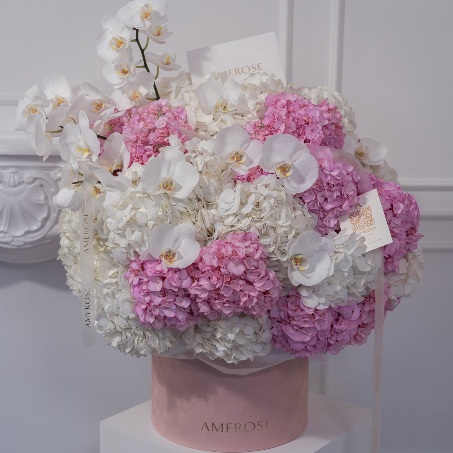 AMEROSE pink velvet hatbox overflowing with white and pink hydrangeas and white phalaenopsis orchids in an ombre cloud arrangement — luxury hatbox flowers London