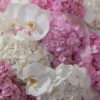 Close-up of white phalaenopsis orchids nestled among pink and white hydrangeas with AMEROSE sheer gold ribbon — luxury flower arrangement detail London